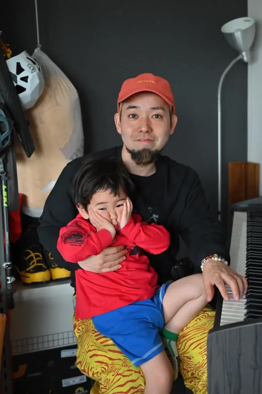 赤いキャップをかぶった槇野翔太さんと、膝の上で笑う息子さんのツーショット
